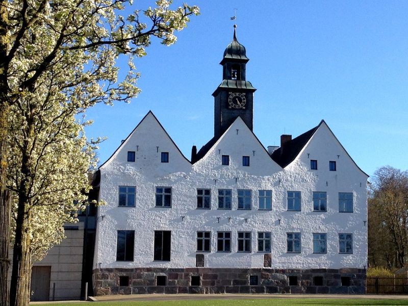 Weißes Herrenhaus unterm blauen Himmel im Sonnenschein.
