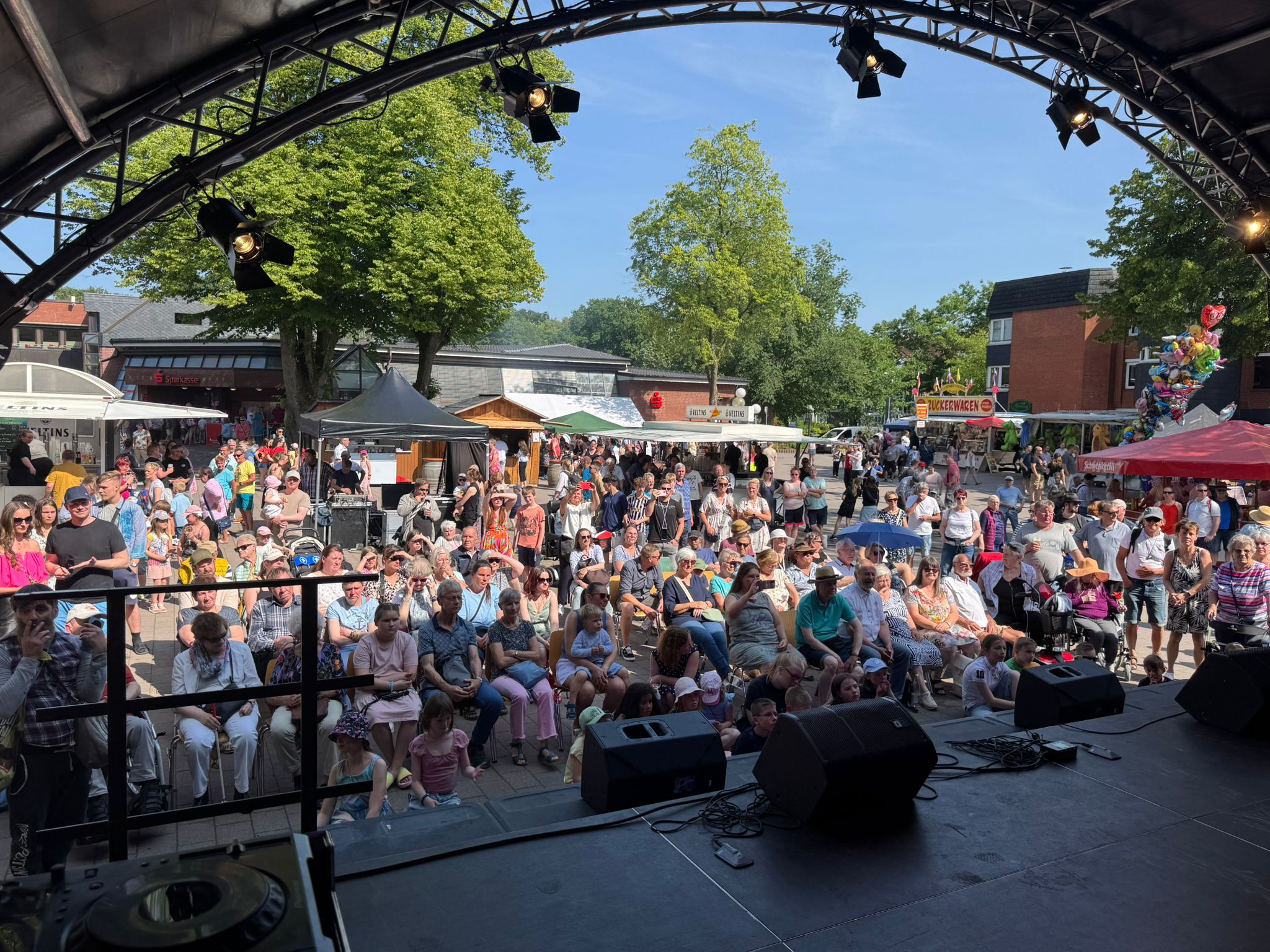 Blick von der Bühne auf den mit Zuschauern gefüllten Marktplatz im Sonnenschein