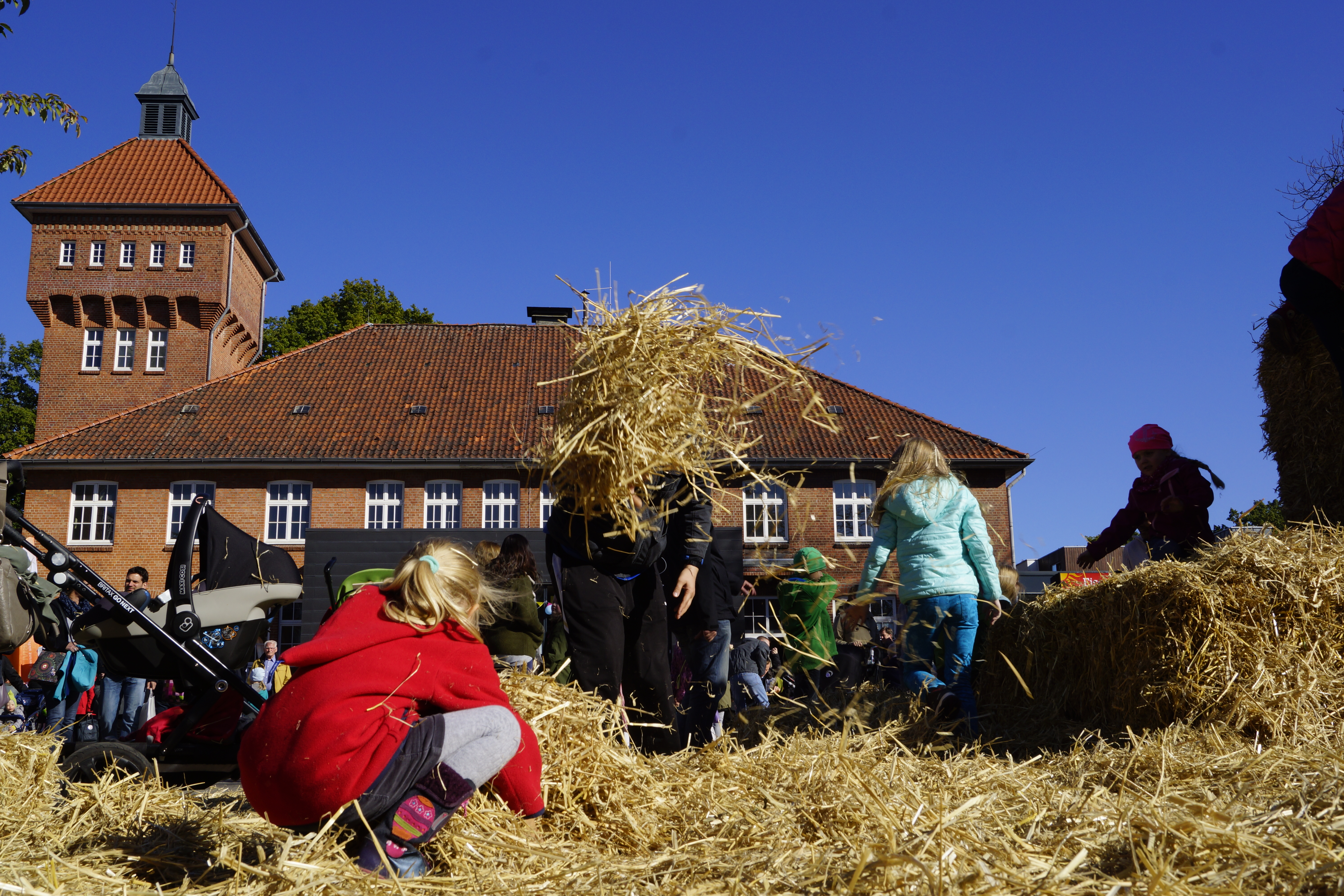 Kinder spielen auf einer Strohballenburg auf dem Alsterdorfer Markt